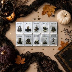 May include: Ten rectangular playing cards arranged in two rows, each labeled JOKER at the top. The cards feature distinct dark illustrations including a figure, a mirror, a dancer, a bat, a wolf, a moon, a clock, a book, a broom, and a person.