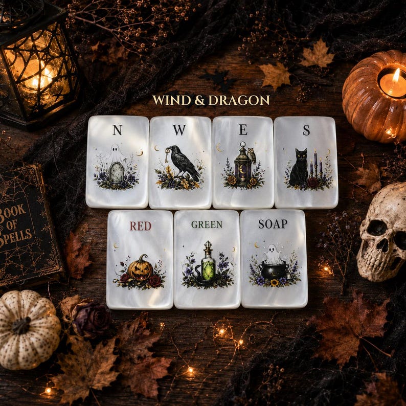 May include: Seven rectangular white tiles featuring illustrations of a ghost, raven, lantern, cat, pumpkin, potion bottle, and cauldron. Each tile displays a letter or word including N, W, E, S, RED, GREEN, and SOAP, arranged in two rows.