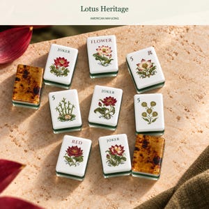 May include: A collection of American Mahjong tiles featuring white surfaces with botanical illustrations of lotus flowers, bamboo, and seed pods. Several tiles are labeled with the text JOKER, FLOWER, or RED, while others display the number 5 and Chinese characters.
