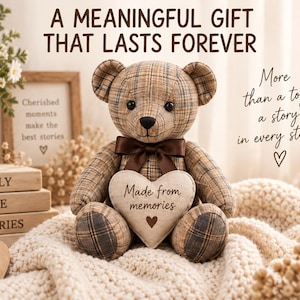 May include: A brown plaid teddy bear with a dark brown satin neck ribbon, holding a cream-coloured heart-shaped pillow embroidered with the text Made from memories. The bear is surrounded by decorative items including books and flowers.