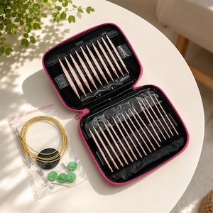 May include: A set of rose gold knitting needles stored in a black zippered case with pink trim. The set includes multiple needle tips, gold-colored circular cables in a plastic bag, and small green circular stoppers and metal tightening keys.