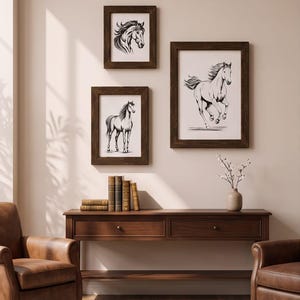 Könnte beinhalten: Drei gerahmte schwarz-weiße Pferdeillustrationen hängen an einer Wand über einem Holzkonsolentisch. Die Kunstwerke zeigen einen Pferdekopf, ein stehendes Pferd und ein galoppierendes Pferd in dunkelbraunen Holzrahmen.