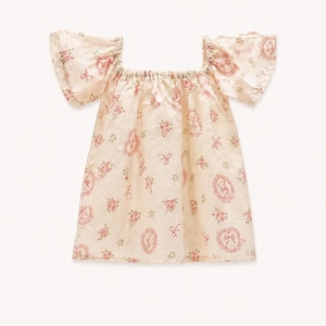 May include: A cream-colored blouse featuring a square neckline and short flutter sleeves. The fabric is decorated with a repeating pattern of small pink floral clusters, delicate bows, and oval-shaped frames containing intricate illustrations.