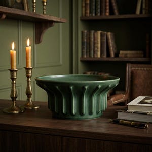 Puede incluir: Un cuenco de cerámica verde profundo con un diseño exterior acanalado de costillas verticales. El cuenco presenta un acabado mate suave y un borde acampanado, colocado sobre una superficie de madera oscura junto a dos candelabros de latón con velas encendidas.