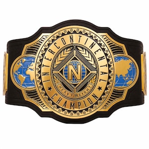 Puede incluir: Un cinturón de campeonato con una gran placa central dorada con el texto INTERCONTINENTAL HEAVYWEIGHT CHAMPION y un emblema N central. El diseño incluye incrustaciones de globos terráqueos azules en los laterales, sobre una correa negra texturizada.