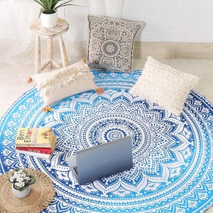 May include: A round fabric tapestry featuring a blue and white mandala pattern with intricate geometric and floral motifs. The circular textile displays a gradient effect, transitioning from deep blue at the center to light blue at the edges.