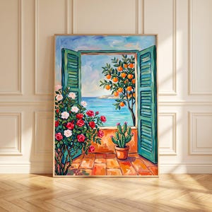 Può includere: Un dipinto incorniciato raffigura una finestra aperta con persiane verdi che si affaccia su un mare blu. Sulla destra si trova un albero di arance con frutti luminosi, mentre a sinistra cresce un cespuglio di rose rosse e bianche. Un cactus in vaso.