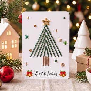 Könnte beinhalten: Eine weiße rechteckige Grußkarte mit einem stilisierten Weihnachtsbaum aus grünem Faden, gekrönt von einem goldenen Stern. Die Karte enthält kleine braune Knöpfe, grüne Perlen, goldene Akzente, den Text Best Wishes und zwei goldene Glocken.