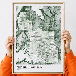 May include: A framed topographic map print of Zion National Park featuring dark green terrain shading, white contour lines, and black text labels for peaks and landmarks. The bottom left corner displays the text Zion National Park.