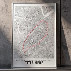 Peut inclure: Une impression de carte topographique encadrée présentant un relief de terrain en niveaux de gris avec un chemin tracé en rouge. La partie inférieure inclut le texte "Custom Message here (distance, duration, elevation, other ...)" et "TITLE HERE" en noir.