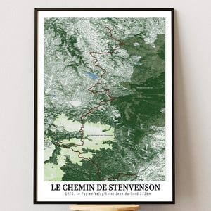 Peut inclure: Une affiche cartographique topographique encadrée intitulée LE CHEMIN DE STENVENSON GR70 : Le Puy-en-Velay/Saint-Jean-du-Gard 272km. La carte présente un sentier rouge foncé serpentant à travers des zones forestières vertes et blanches.