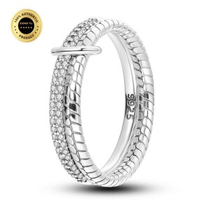 May include: A silver-toned ring featuring a dual-band design. One band has a smooth, twisted rope-like texture, while the other is encrusted with small, clear pavé stones. A horizontal bar connects the two bands. The interior is stamped with S925.