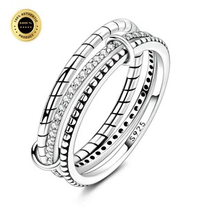 May include: A silver-toned ring featuring three interconnected bands. One band is smooth with S925 stamped on the side, another has a textured grid pattern, and the central band is encrusted with small clear stones. The design is metallic and polished.