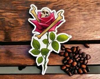 May include: A red rose with a white skull in the centre, surrounded by two crossed bone-like stems. The rose is on a white background.