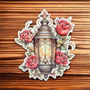 May include: A vintage-style lantern with a glowing light inside, surrounded by red roses and green leaves. The lantern is made of metal and has a decorative design.