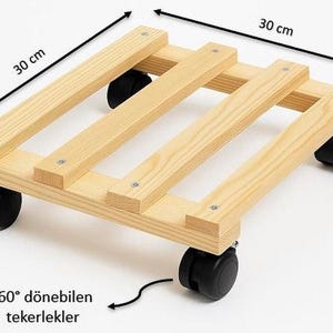 May include: A square wooden plant caddy featuring four light-colored wooden slats held together by metal screws. The base is equipped with four black plastic swivel casters. The dimensions are clearly marked as 30 cm by 30 cm on the image.