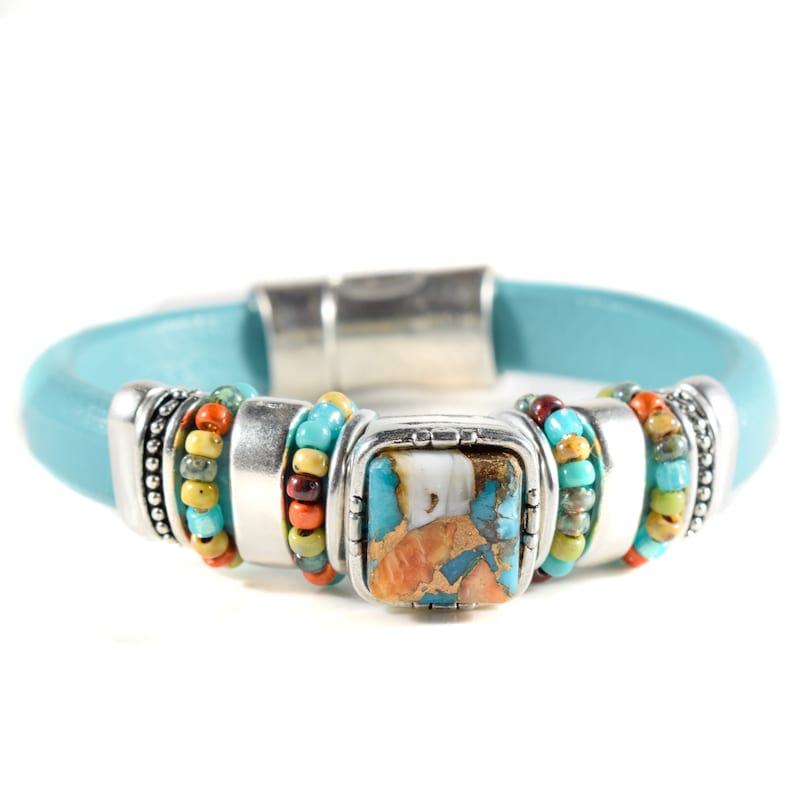 May include: A turquoise leather bracelet with a silver magnetic clasp. The bracelet features a square turquoise stone with copper accents, surrounded by silver metal and colorful beaded accents. A stylish piece of jewelry.