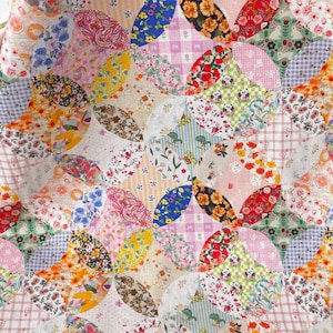 May include: A quilt featuring a repeating pattern of interlocking circles and squares. The fabric displays a variety of colorful floral, plaid, and gingham prints in shades of pink, yellow, blue, red, and green. The text fabricmade.etsy.com is visible.
