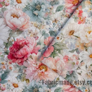 May include: Floral fabric with a watercolor effect. The design features large pink peonies, white daisies, and other flowers in shades of pink, peach, and blue-green against a white background. The fabric is folded, showing the pattern from different angles.