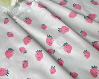 May include: White cotton fabric with a repeating pattern of pink strawberries. The strawberries are hand-painted and have a watercolour effect. The fabric is ideal for quilting, sewing, and crafting.