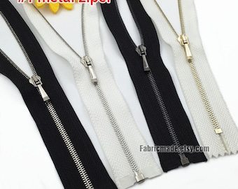 May include: Four metal zippers in different colors: black, white, silver, and gold. The zippers are all closed and have a metal slider. #1 metal zipper