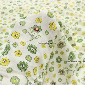 Peut inclure: Tissu blanc avec un motif r&eacute;p&eacute;titif de petites fleurs jaunes et vertes. Le tissu est pli&eacute; en deux et le texte "12#" est visible en haut &agrave; gauche.