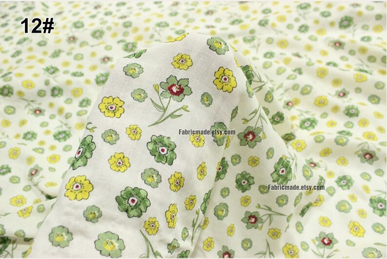 Peut inclure: Tissu blanc avec un motif r&eacute;p&eacute;titif de petites fleurs jaunes et vertes. Le tissu est pli&eacute; en deux et le texte "12#" est visible en haut &agrave; gauche.