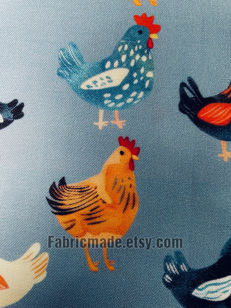 May include: A light blue fabric featuring a repeating pattern of chickens in various colors including yellow, blue, and black, each with a red comb. The text Fabricmade.etsy.com is printed in black across the lower center of the textile surface.