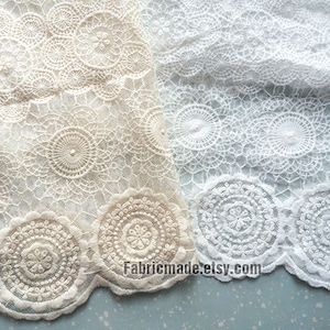 May include: Two pieces of lace fabric featuring a circular floral pattern and a scalloped edge. One piece is beige and the other is white. The text Fabricmade.etsy.com is printed in the center of the image over the lace fabric.