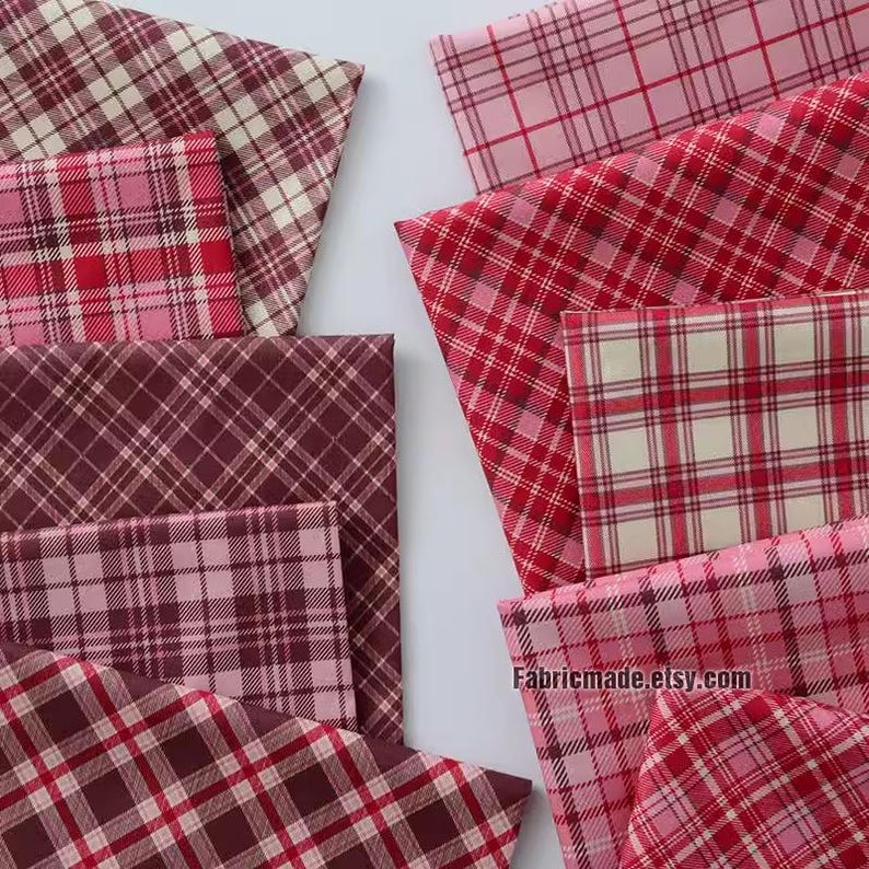May include: Assortment of red, pink, and brown plaid fabric swatches. The fabric has a woven texture and is perfect for quilting, sewing, and crafting projects.