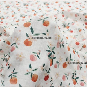 Peut inclure: Tissu en coton blanc avec un motif r&eacute;p&eacute;t&eacute; de fruits orange, de feuilles vertes et de fleurs roses. Le tissu est pli&eacute; et le texte "14#" est visible dans le coin sup&eacute;rieur gauche.