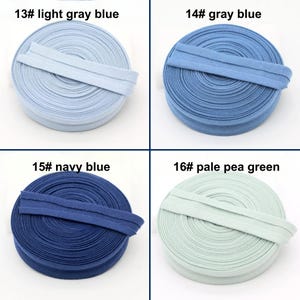 May include: Four spools of bias tape in various colors. The colors are light gray blue, gray blue, navy blue, and pale pea green. Each spool has a label with a number and color name. The text on the labels is clear and easy to read.
