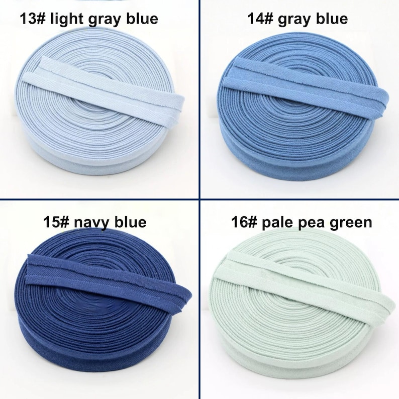 May include: Four spools of bias tape in various colors. The colors are light gray blue, gray blue, navy blue, and pale pea green. Each spool has a label with a number and color name. The text on the labels is clear and easy to read.