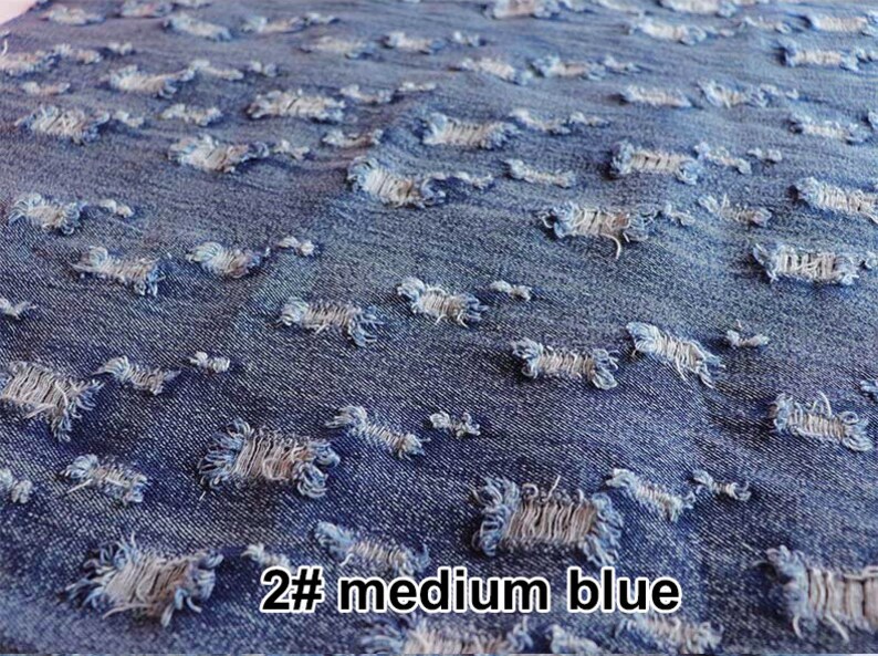 May include: Close-up of a medium blue denim fabric with distressed holes. The fabric has a rough texture and a faded appearance. The text "2# medium blue" is visible in the bottom right corner of the image.