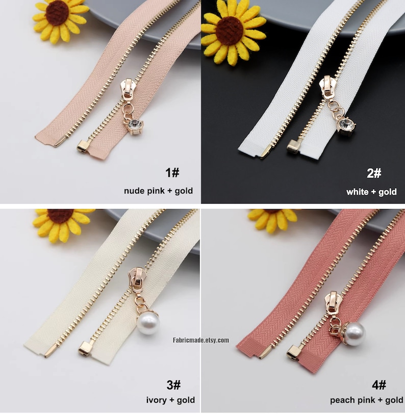 May include: Four different zipper pulls with gold metal zippers and different colored zipper tapes. The zipper pulls are decorated with a crystal, a pearl, and a pearl. The zipper tapes are nude pink, white, ivory, and peach pink.