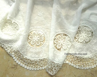 May include: White cotton fabric with a delicate lace trim and embroidered floral designs. The fabric features a scalloped edge and a repeating pattern of circular lace motifs.