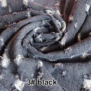 May include: Close-up of a dark gray denim fabric with a distressed, ripped look. The fabric is folded and textured, showing the frayed edges of the rips. The text "3# black" is visible in the lower right corner of the image.