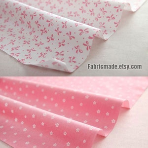 May include: Two pieces of pink fabric with white patterns. The top piece has a white background with pink bows. The bottom piece has a pink background with white flowers. Fabricmade.etsy.com is printed on both pieces.