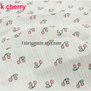 May include: White fabric with a repeating pattern of pink cherries with green stems and leaves. The text "2# pink cherry" is in the top left corner of the image.
