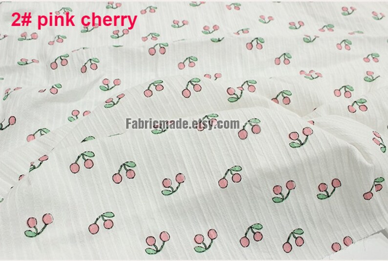 May include: White fabric with a repeating pattern of pink cherries with green stems and leaves. The text "2# pink cherry" is in the top left corner of the image.