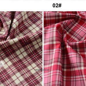 May include: Two swatches of plaid fabric. The first swatch is a cream and burgundy plaid with a measurement of 2.5 inches. The second swatch is a pink and red plaid with a measurement of 2.2 inches.