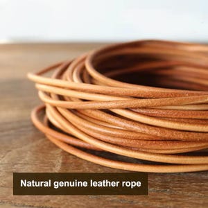 May include: A coil of natural genuine leather rope with a smooth, rounded texture and a warm tan colour. The leather cord is wound into a circular shape, showcasing the consistent thickness and flexible material of the natural leather rope.