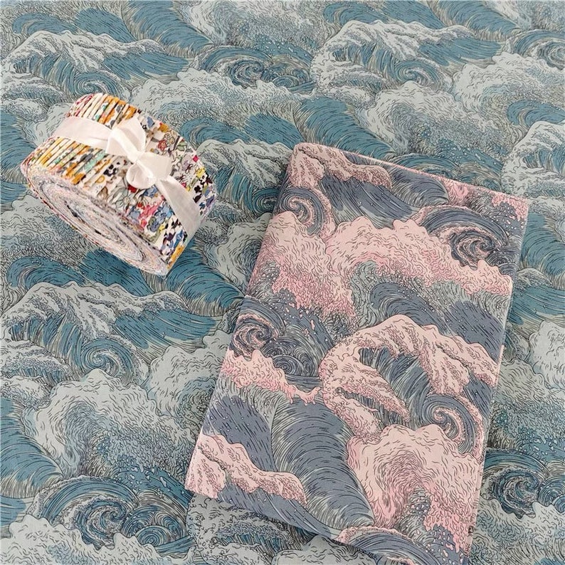 May include: A roll of patterned fabric tied with a white ribbon, next to a folded piece of fabric. The fabrics feature a blue and white wave design, with a pink and gray wave pattern on the folded piece. The fabrics are suitable for sewing and crafting.