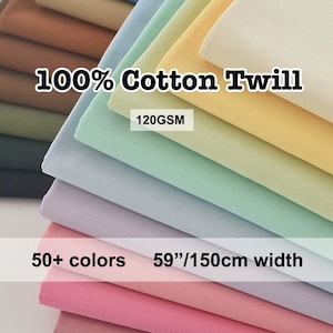 Puede incluir: Una pila de muestras de tela de sarga 100% algodón de colores pastel. La imagen muestra una variedad de colores, incluyendo rosa, morado, verde y amarillo. El texto indica más de 50 colores disponibles con un ancho de 150 cm. La tela es de 120GSM.