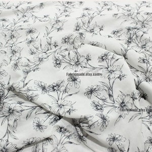 Peut inclure: Tissu blanc avec un imprim&eacute; floral noir. Le tissu a une texture subtile et une sensation douce et fluide. Les fleurs sont petites et d&eacute;licates, et elles sont dispos&eacute;es en un motif r&eacute;p&eacute;titif. Le tissu est parfait pour une vari&eacute;t&eacute; de projets de couture, tels que des robes, des jupes, des chemisiers et de la d&eacute;coration int&eacute;rieure.