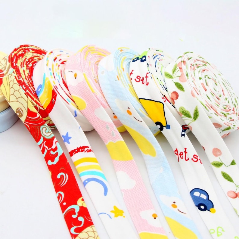 May include: A collection of colorful ribbons with various patterns, including floral, cartoon cars, and clouds. The ribbons are rolled up and displayed in a row, showcasing a variety of designs and colors.