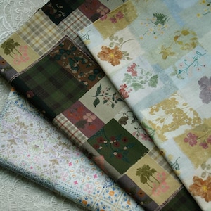 May include: Close-up of several fabric swatches with floral and plaid patterns. The fabrics feature a patchwork design with squares of various colors, including green, brown, and beige. Some squares have floral prints in shades of pink, yellow, and orange.
