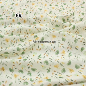 May include: White cotton fabric with a delicate floral pattern featuring small yellow flowers and green leaves. The fabric has a subtle watercolour effect and is perfect for crafting and sewing projects.