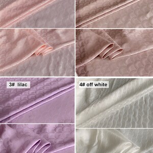 May include: Four fabric swatches with a subtle embossed pattern of overlapping circles. The swatches are in four colors: pink, dirty pink, lilac, and off white.