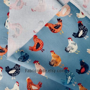 May include: A blue fabric featuring a repeating pattern of chickens in various colors including orange, black, white, and blue. The fabric is folded to reveal a lighter, off-white underside. The text Fabricmade.etsy.com is printed on the fabric.